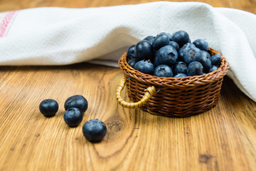 Blueberries in basket on wooden table.