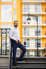 Fototapeta na wymiar Young man weared in classic suit on background of the City. Fashion style guy happy groom weared in white shirt. Street style businessman man portrait. Modern urban wedding walk in old town