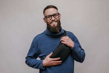 Handsome hipster guy with beard wearing blue blank sweatshirt with waist bag. Mockup for print