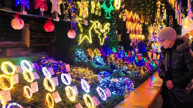 Mujer con gorro mirando guirnaldas de leds de colores navide&ntilde;as