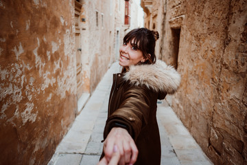 .Pretty young girl traveling around the island of Malta. Knowing its culture and visiting the old capital, Mdina, known as the Silent City. Holding hands with her couple. Lifestyle..