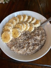 Oatmeal  with seeds and banana on white plate