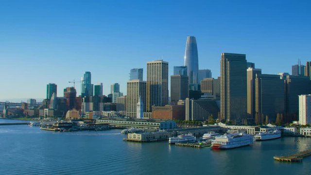 Amazing aerial view of San Francisco skyline. Flyover the Pacific ocean with several ships. Famous skyscrapers over a blue sky. Shot on Red weapon 8K. California, United States.