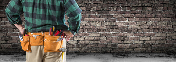 Contractor With Tool Belt Facing Aged Brick Wall Banner