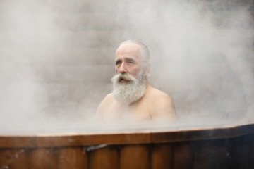 Bearded senior man enjoying thermal bath in thalassotherapy center.
