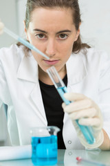 young woman holding glass lab tube with a blue liquid