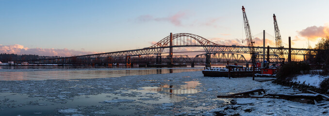 Fototapeta na wymiar Beautiful Panoramic View of Fraser River and Pattullo Bridge in the City during a cold and icy winter sunset. Taken in New Westminster, Vancouver, British Columbia, Canada.