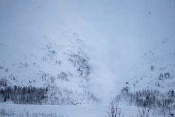 Fototapeta na wymiar An avalanche descends in the snowy mountains beyond the Arctic Circle