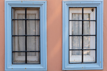 Fototapeta na wymiar Two similar old wooden windows on the wall. The traditional colorful design in island Symi in Greece. 
