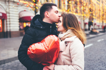 Loving couple on the street kissing on christmas background.