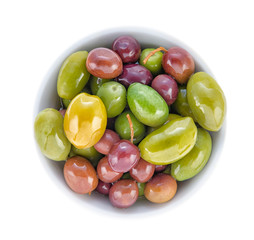 Olives of different grades and sizes in a porcelain bowl. Top view close up.