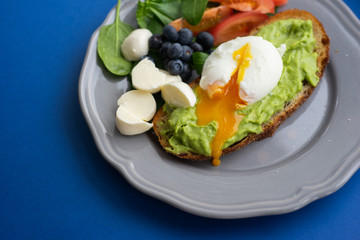 Wholesome tasty full of vitamins and health breakfast with avocado, berries, cheese and tomatoes with basil.