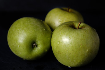 Green apple, fresh and wet isolated on black background