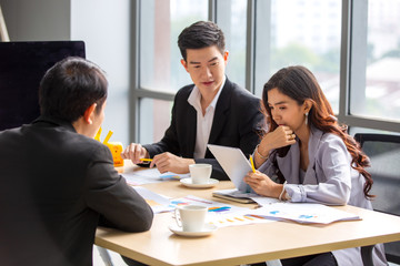 young business team working together at office. Manager pointing at a chart and explaining the analysis about business strategies.