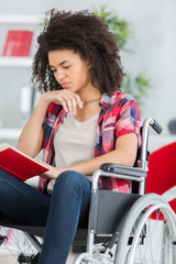 teenage woman on wheelchair reading a book