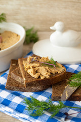 Fresh homemade duck or chicken liver pate in ceramic rustic bowl or ramekin and bread slices with herbs, vertical image