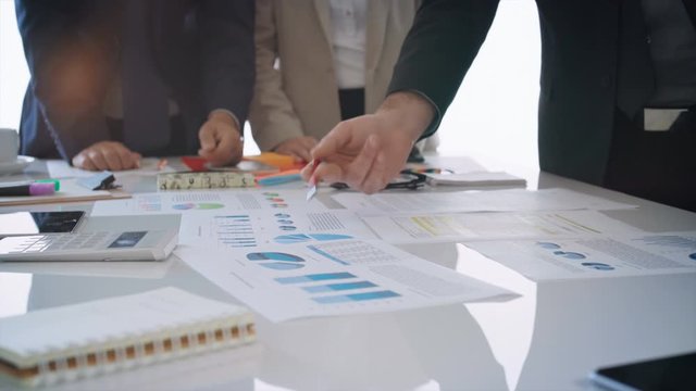 Diverse group of executives having a business meeting. They are discussing over financial data and graphs, showing the development of their company. 