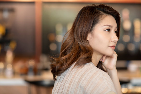 Elegant woman with hand on chin in cafe