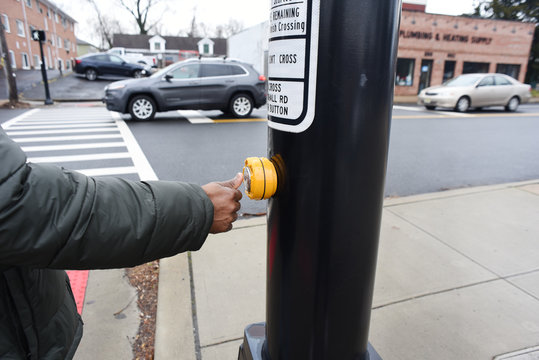 African American pressing the cross button. safety first. A black hand pressing a knob. A cute man trying to cross the road. A man waiting the walk on the zebra crossing