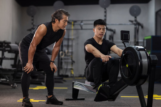 Mature man working out with personal trainer at gym