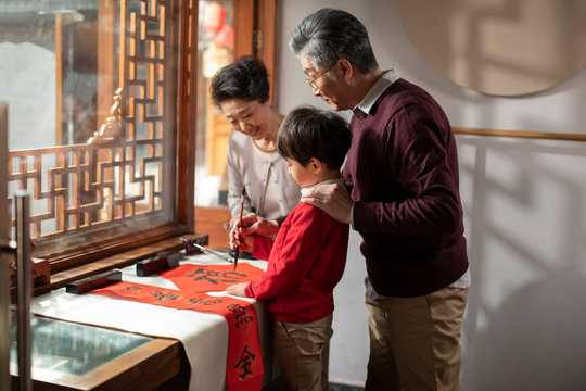 Happy family writing calligraphy on couplets