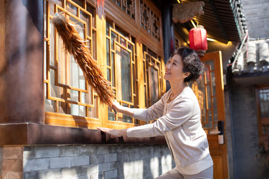 Happy senior woman dusting