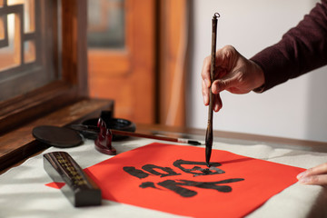 Senior man writing calligraphy on couplets