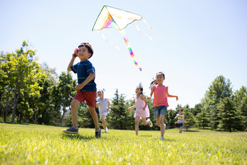 Happy children running with a kite on meadow