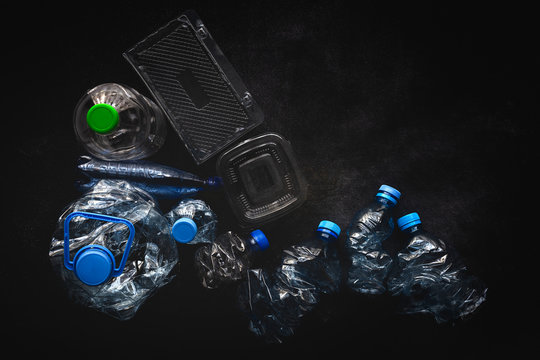 Top view of plastic bottles and boxes arranged on dark background surface