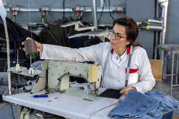 Working woman hands in textile factory sewing on industrial sewing machine. Industrial production