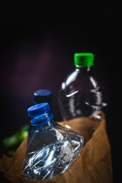 Dirty paper sack with discarded plastic bottles placed on black background