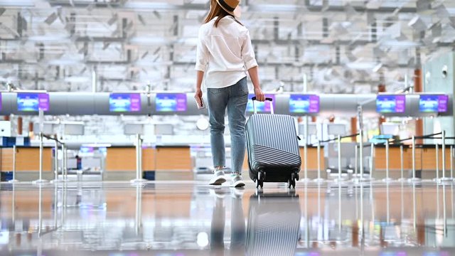 Female carrying luggage go to check-in counter at a modern airport