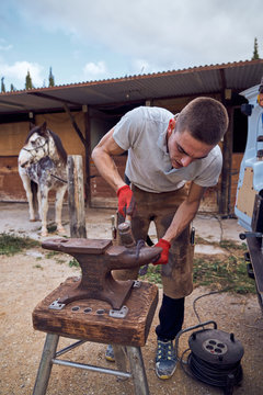 Blacksmith boy working on the anvil changing the horseshoe to a leg with tools