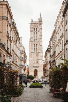 View of aged tower with arch from colorful street of Paris