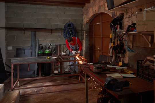 Interior of a workshop with a blacksmith working with the electric cutting disc