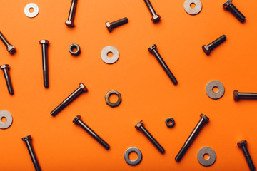 Bolts and nuts closeup on orange background.