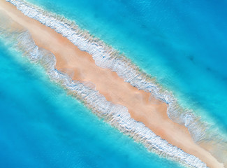 Aerial view of transparent blue sea with waves on the both sides and empty sandy beach at sunset. Summer holiday in Zanzibar, Africa. Tropical landscape with lagoon, white sand and ocean. Top view - obrazy, fototapety, plakaty