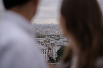 Silhouettes of a hugging couple watching Paris from a high point of the city.