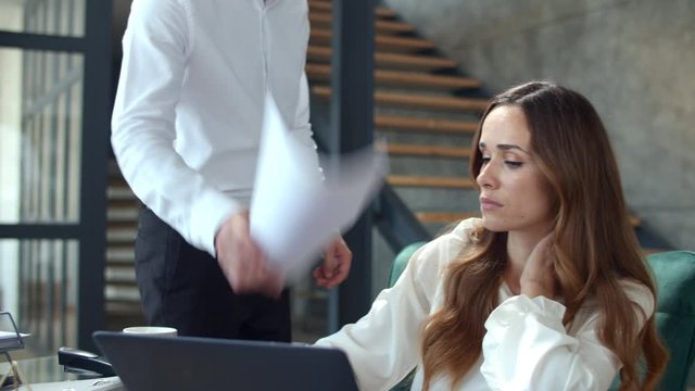 Angry boss throwing papers in front of secretary in slow motion.