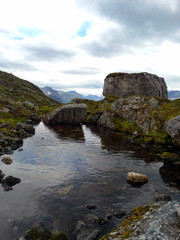 Fototapeta na wymiar little lake with rocks at a mountain in Norway