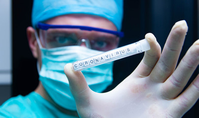 A scientist holds in his hand a test tube with the virus coronavirus.