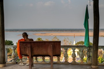  Buddhist monk watch the Mekong River sitting on a bench inside Wat Hanchey, a Buddhist temple near Kampong Cham city, Cambodia - obrazy, fototapety, plakaty