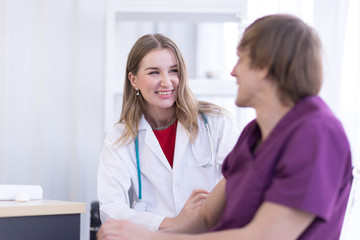 Portrait Of Female Doctor Wearing White Coat is Examining male Patient in the hospital.