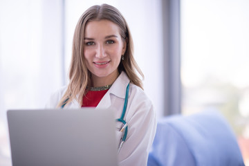 Portrait Of Female Doctor Wearing White Coat with stethoscope, smiling to camera