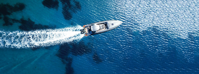 Aerial drone top down ultra wide photo of inflatable speed boat cruising in high speed in deep blue...