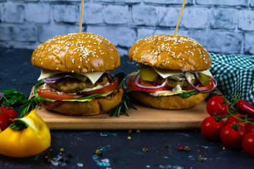 Two homemade beef burgers with mushrooms, micro greens, red onion on wooden cutting board