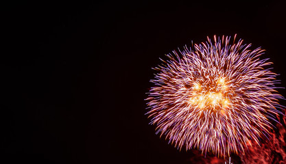 Large red, purple, gold, and white starburst fireworks with a black background