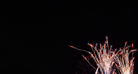 Red and gold streaming wheat shaped fireworks with white accents with a black background