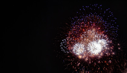 Large red, white, blue, and gold expanding fireworks with a black background