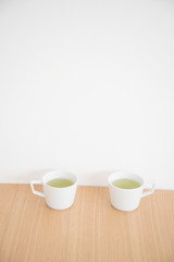 Fototapeta na wymiar 白い２つのマグカップと緑茶